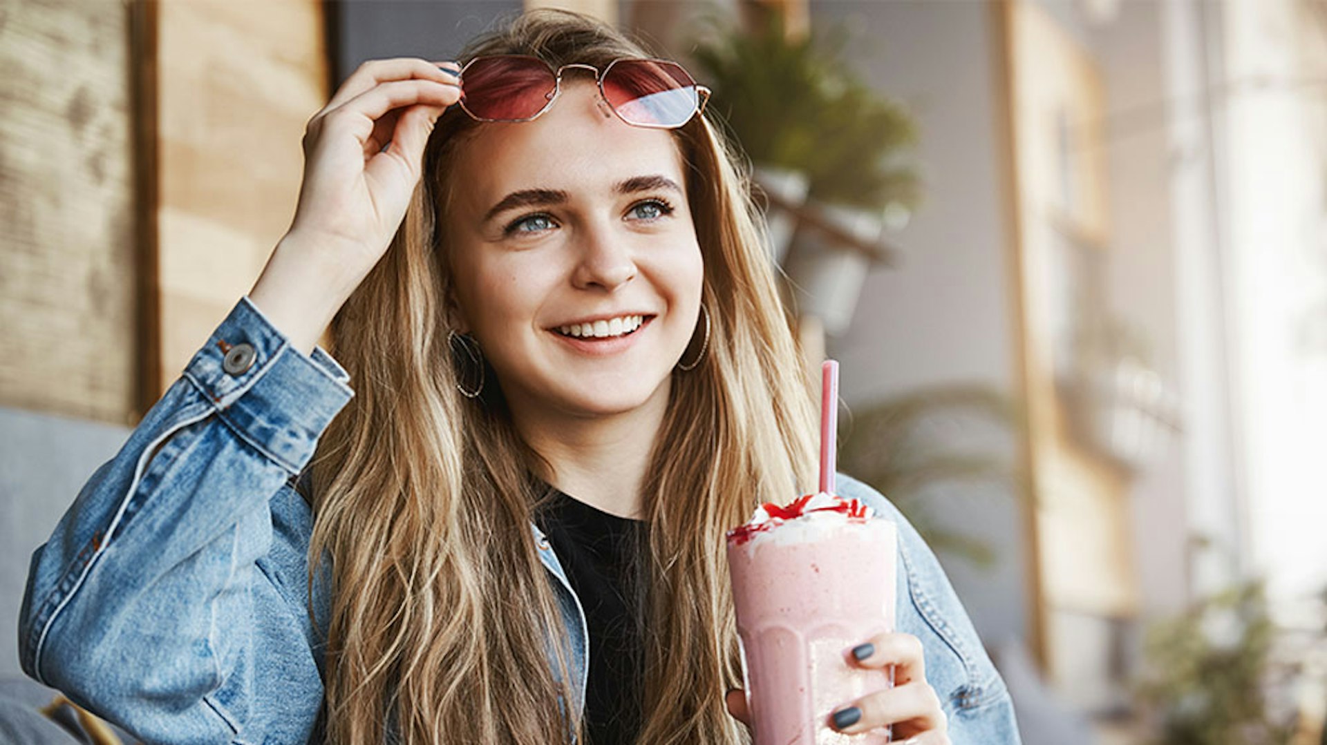 A woman with a shake pushing up her sunglasses