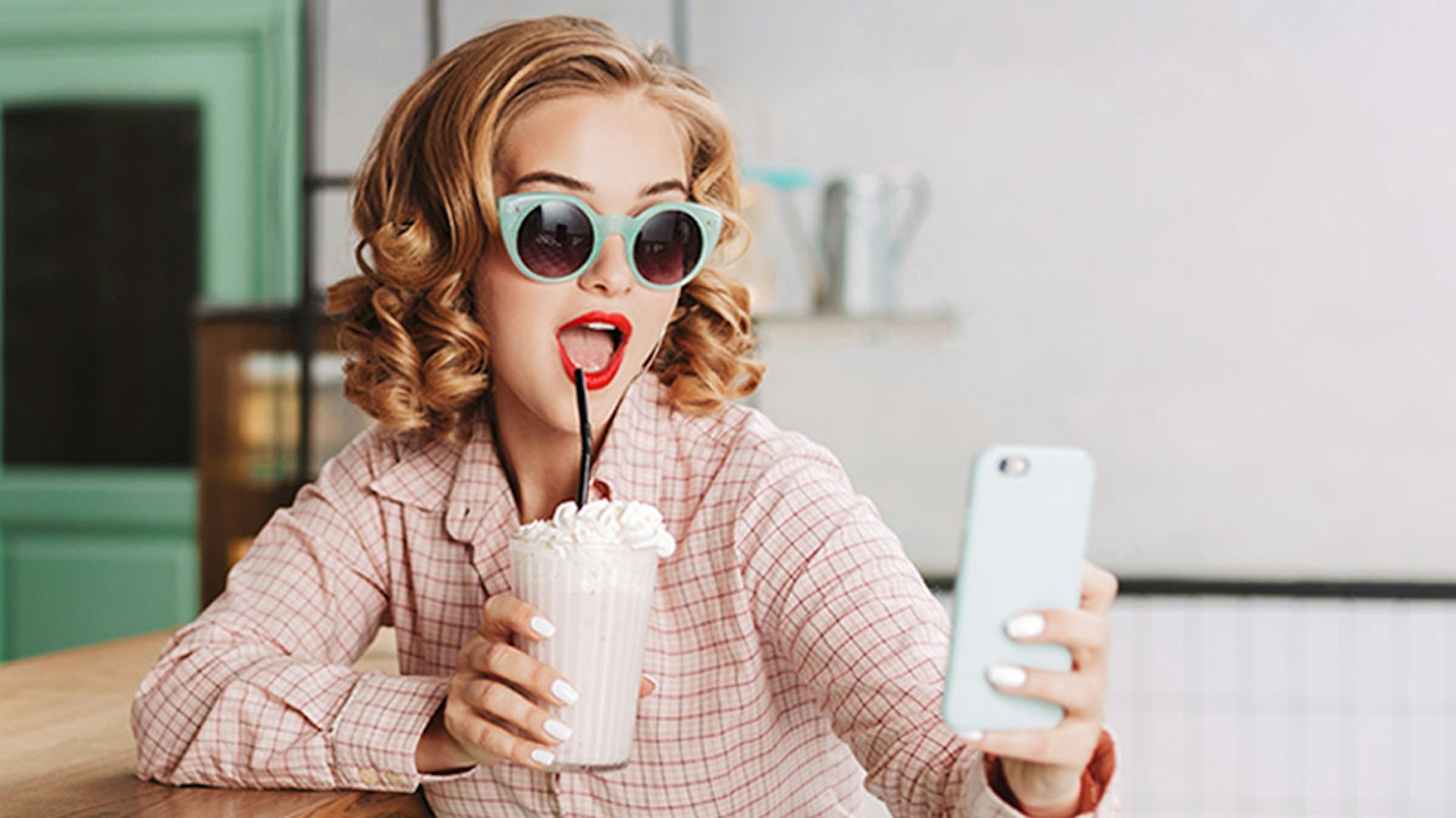 A woman holding a shake and taking a selfie