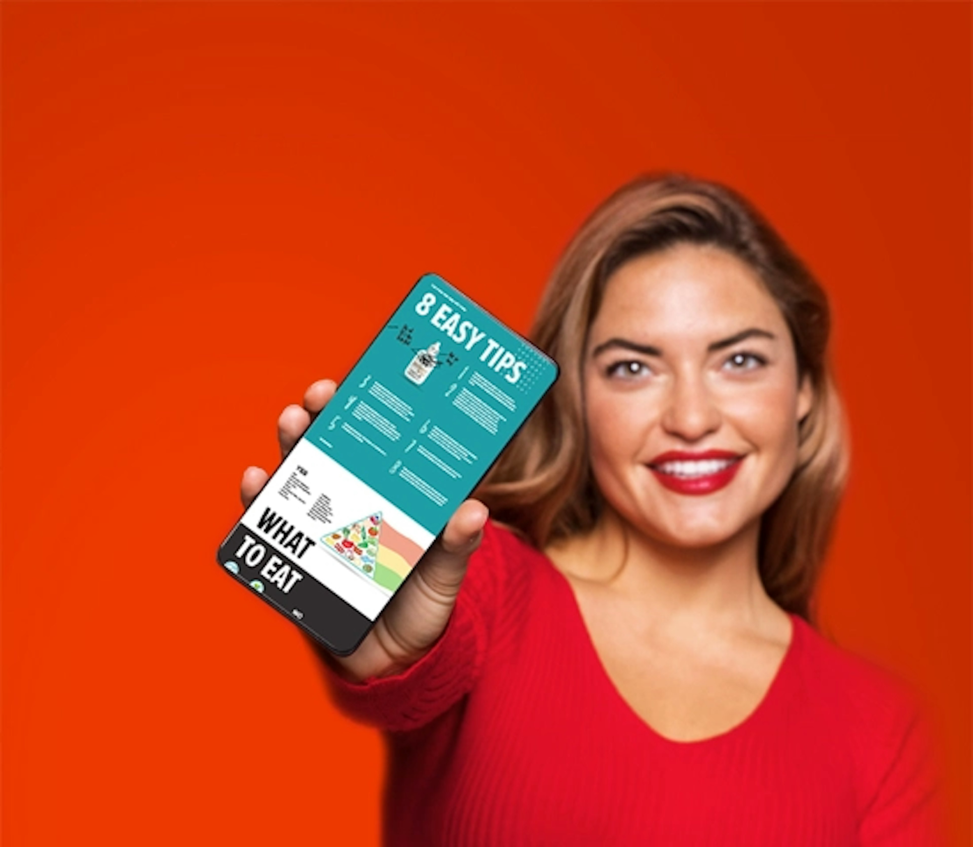 A blonde woman in a red shirt smiling and holding up a phone showing the digital keto start guide