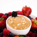 Close up - bowl of Salted Caramel sauce surrounded by mixed berries.