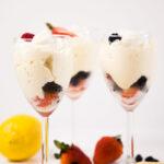 Close up - Three glass goblets filled with berries and Lemon Mousse. Surrounded by berries and lemons.